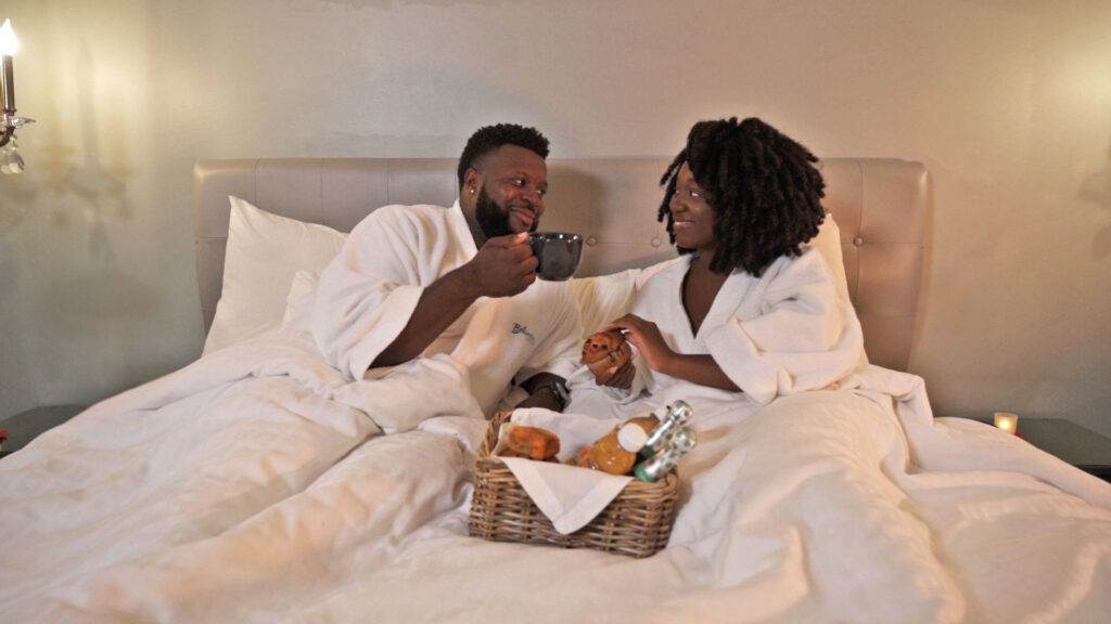 Romantic couple in bed enjoying food from a basket.